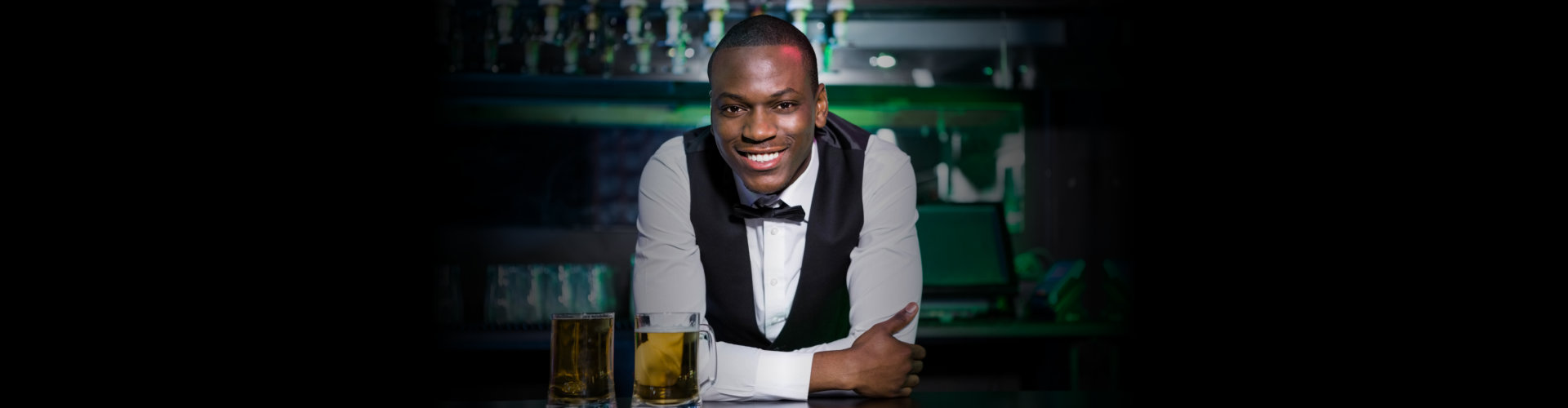 Portrait of bartender leaning and smiling on bar counter